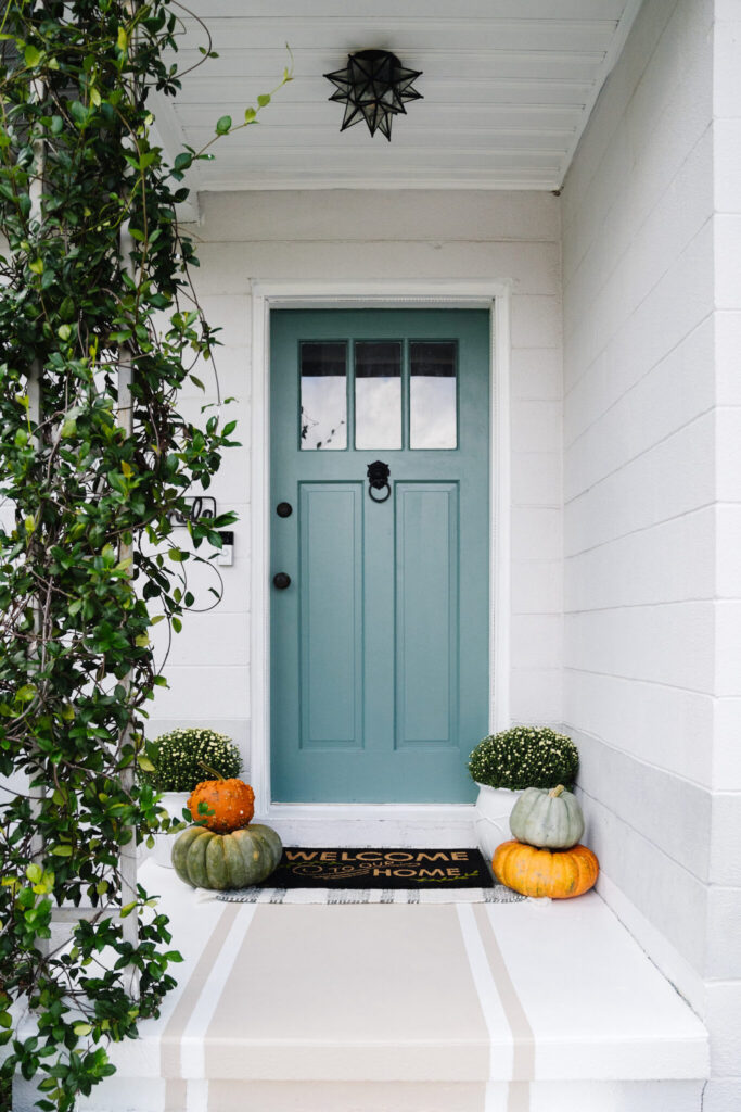 blue door with pumpkins on porch