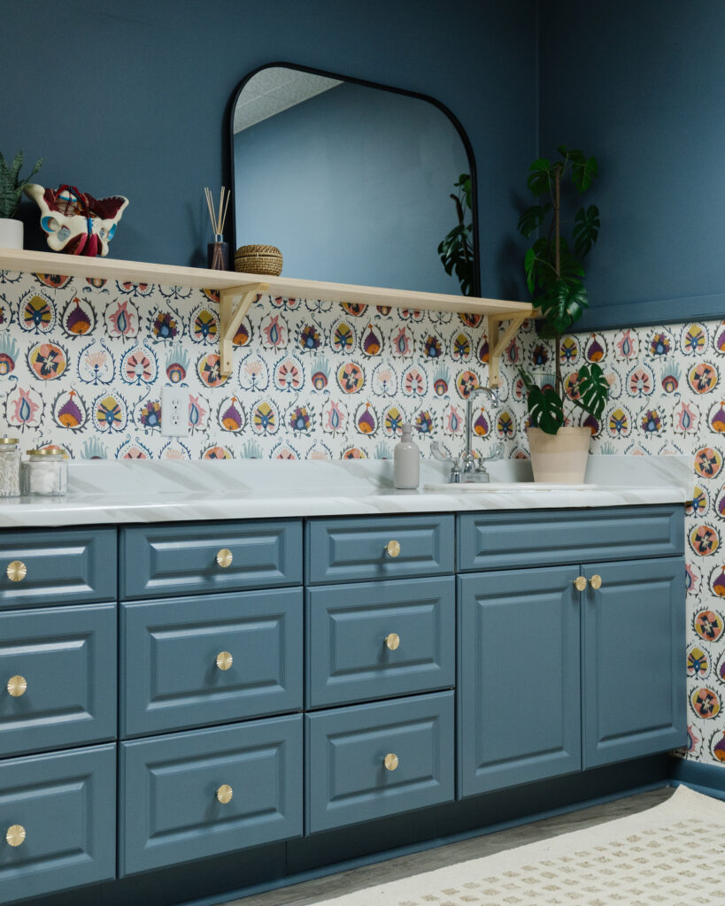 blue cabinets and walls, and patterned wallpaper